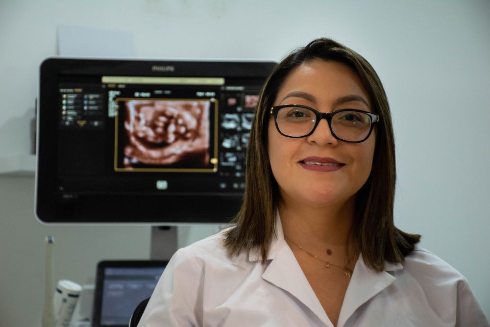 La Dra. Jessica Chasi junto al ecógrafo con una imagen 3D